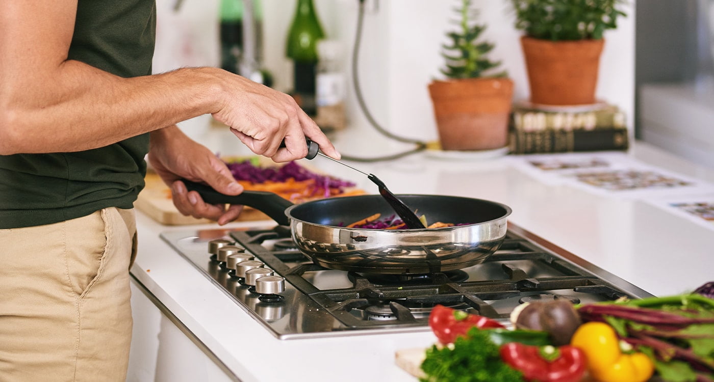 person cooking vegetables in a pan on the stove